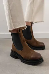 Botas de cuero color marrón oscuro, estilo Chelsea, con elástico lateral negro y suela track negra. Incluye correa de cuero desmontable con hebilla.