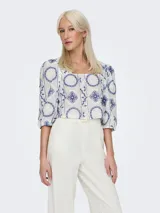 Top corto blanco con estampado de flores azules, cuello cuadrado y mangas cortas abullonadas.