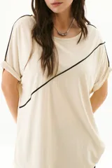 Remera negra de corte holgado con cuello redondo y mangas cortas con dobladillo. Presenta una línea diagonal blanca que cruza el frente desde el hombro hasta la cadera.