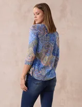 Blusa de modal estampada con motivos paisley en tonos azules, naranjas y amarillos. Tiene escote redondo y mangas tres cuartos.