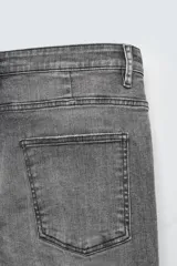 Pantalón de jean azul oscuro con efecto lavado y roturas en las rodillas, de corte ajustado al cuerpo desde la cintura hasta el tobillo.