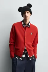 Cárdigan rojo de punto con cuello redondo, manga larga y cierre frontal con botones. Tiene un parche de Minnie Mouse en el pecho.