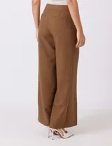 Pantalón sastrero color marrón, de tiro alto y corte recto, con un largo al tobillo. Presenta pretina limpia con cierre interno, bolsillos funcionales en la delantera y plisado que aporta volumen. La trasera tiene bolsillos ojal simulados.