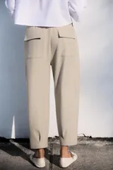 Pantalón tobillero negro de tiro medio con cintura elástica en la espalda, bolsillos delanteros y bolsillos de parche con solapa en la espalda. El bajo está acabado con pinzas y el cierre frontal es con cremallera y botón.