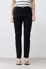 Pantalón de jean negro, corte slim fit, tiro medio y largo hasta el tobillo.