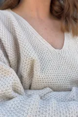 Sweater de punto color crudo con escote en V y mangas largas.