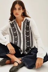 Camisa blanca de manga larga con cuello mao y escote en V, con bordados negros en el frente y puños.