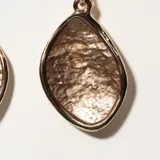 Par de aros colgantes dorados con forma de gota y textura irregular.