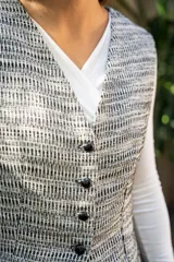 Chaleco tipo sastre con estampado a cuadros en tonos crudo y negro, con botones al frente y corte entallado.