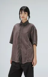 Camisa manga corta color gris con efecto desgastado, corte holgado y cierre frontal con botones.