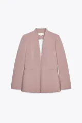 Blazer color rosa palo, sin solapa, de corte recto y manga larga. Presenta bolsillos de ojal en el delantero y cierre frontal con gancho metálico.