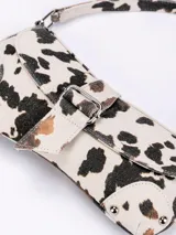 Bolso de mano con estampado animal print en tonos beige y negro, con cierre frontal y asa corta.