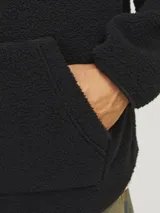 Canguro negro de tejido teddy con capucha forrada, cordones ajustables y bolsillo tipo canguro. Estampa frontal con la palabra 'Originals' en relieve.