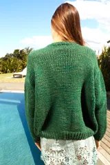 Sweater tejido de lana color verde con bordado de flor y la palabra "Bloom" en el frente. De calce holgado, cuello redondo y puños ajustados.