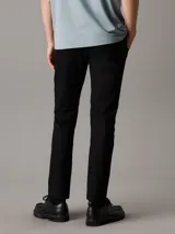 Pantalón chino negro de corte tapered, confeccionado en sarga de algodón elástica. Cuenta con cierre de botón y cremallera, bolsillos con ranura y bolsillos traseros de ojal.