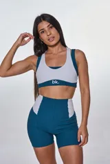 Conjunto deportivo de top y short tiro alto, color verde con detalles en gris. El top es de corte deportivo con breteles anchos y logo en el frente. El short es ajustado al cuerpo con paneles laterales en contraste.