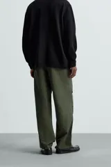 Pantalón verde militar de corte relaxed fit confeccionado en tejido técnico ligero. Cuenta con cintura elástica ajustable con cordón interior, bolsillos frontales y traseros con solapa, pliegues en las rodillas y bajo ajustable con elástico.