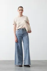 Remera blanca de manga corta con cuello redondo y bordado floral en relieve de color beige claro en el frente.