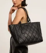 Cartera shopper grande negra de material sintético con textura capitoneada, doble asa de hombro y cierre de cremallera. Incluye colgante de borla.