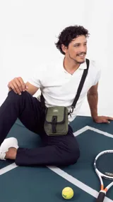 Morral verde militar con cierre, bolsillo delantero con presilla y broche de plástico, bolsillos internos y correa larga regulable.