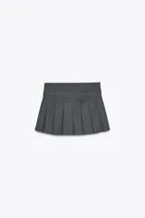 Minifalda gris de tiro alto con tablas y cinturón con hebilla metálica. Cierre lateral con cremallera oculta.