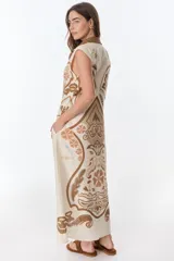 Vestido largo color crema con estampado cachemir en tonos marrones, con cuello camisero, sin mangas y abotonado al frente.