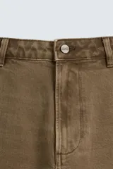 Bermuda color verde militar, de corte relaxed fit, con bolsillos frontales y traseros tipo plaqué, detalle de tira y bolsillo multifunción en la pierna, y bajo irregular.
