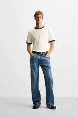 Camiseta azul marino de corte recto, con cuello redondo y mangas cortas. Presenta ribete blanco en cuello y mangas.
