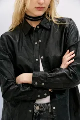 Camisa de cuero ovino negro con efecto arrugado, de moldería amplia, con cuello camisero y botones a presión con logo.
