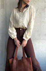 Camisa color manteca con bordado inglés, cuello en V y mangas largas abullonadas.