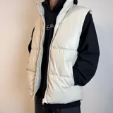 Chaleco puffer color crema, con cierre frontal y bolsillos laterales.
