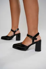 Sandalias negras de charol con punta cuadrada, tira sobre el empeine con hebilla metálica y tacón ancho.