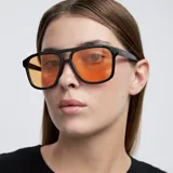Lentes de sol de aviador con montura negra y lentes naranjas. Fabricados con materiales bio-based G850 y patillas de propionato de celulosa. Cuentan con protección UV400.
