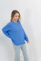 Sweater azul de punto medio, amplio, suave, con escote a la base y puños en mangas y en acabado inferior.