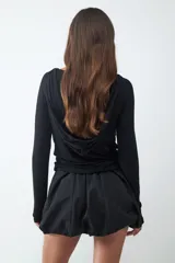 Minifalda negra de tiro bajo con silueta tipo globo, confeccionada en tejido técnico con cintura elástica oculta y bajo redondeado.