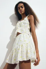 Minifalda blanca de algodón con estampado floral amarillo, cintura elástica y volados.