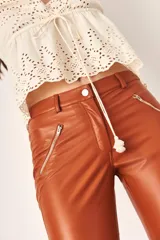 Pantalón legging de cuero color marrón con cierre en los bolsillos.