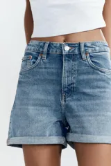 Bermuda de jean celeste, corte mom fit, tiro alto, con cinco bolsillos y ruedo doblado.