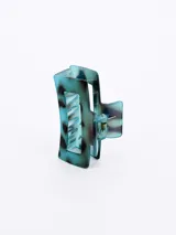 Broche para el pelo con forma rectangular, color verde azulado con manchas negras.