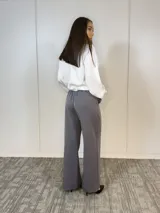 Pantalón de vestir gris con corte palazzo, cintura alta con elástico y cinturón con hebilla dorada.