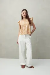 Blusa color beige con estampado paisley blanco, cuello redondo y mangas cortas con volados.