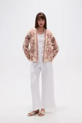 Chaqueta tipo kimono de tejido grueso color crema, con bordado floral en tonos rosados. Presenta un corte holgado y mangas anchas.