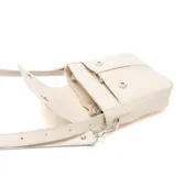 Bandolera mediana color beige con textura tipo cuero repujado y solapa lisa. Tiene correa ajustable con herrajes plateados y logo metálico en la solapa.
