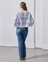 Buzo calado de acrílico, marca Sioni, color celeste y blanco, con cuello a la base y mangas tres cuartos.