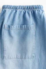 Pantalón denim celeste de corte ancho, con cintura elastizada y cordón ajustable.