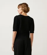 Blusa negra de manga corta con cuello redondo y textura de punto con patrón de corazones o escamas.