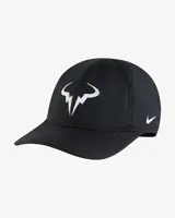 Gorra negra de tenis Nike Club, modelo Rafa Nadal, con logo del toro bordado en blanco en el lateral y logo de Nike bordado en blanco en la parte posterior.