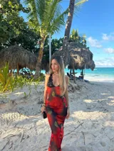 Vestido midi de microtul rojo con estampado de rosas y hojas verdes, escote en V con encaje negro y breteles finos regulables en la espalda.
