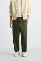 Pantalón de hombre color beige, corte carrot fit, con cintura elástica ajustable con cordón, bolsillos frontales y bolsillo trasero de plastrón.