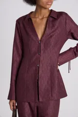 Camisa color borgoña con textura acanalada, cuello camisero, escote en V profundo y cierre frontal con botones.